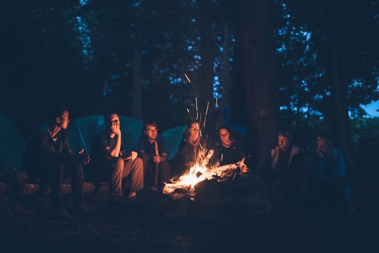 Campfire burning at dusk with dark hills behind